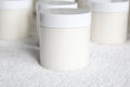 White cylindrical containers of body butter by Busy Little Body on a textured white surface