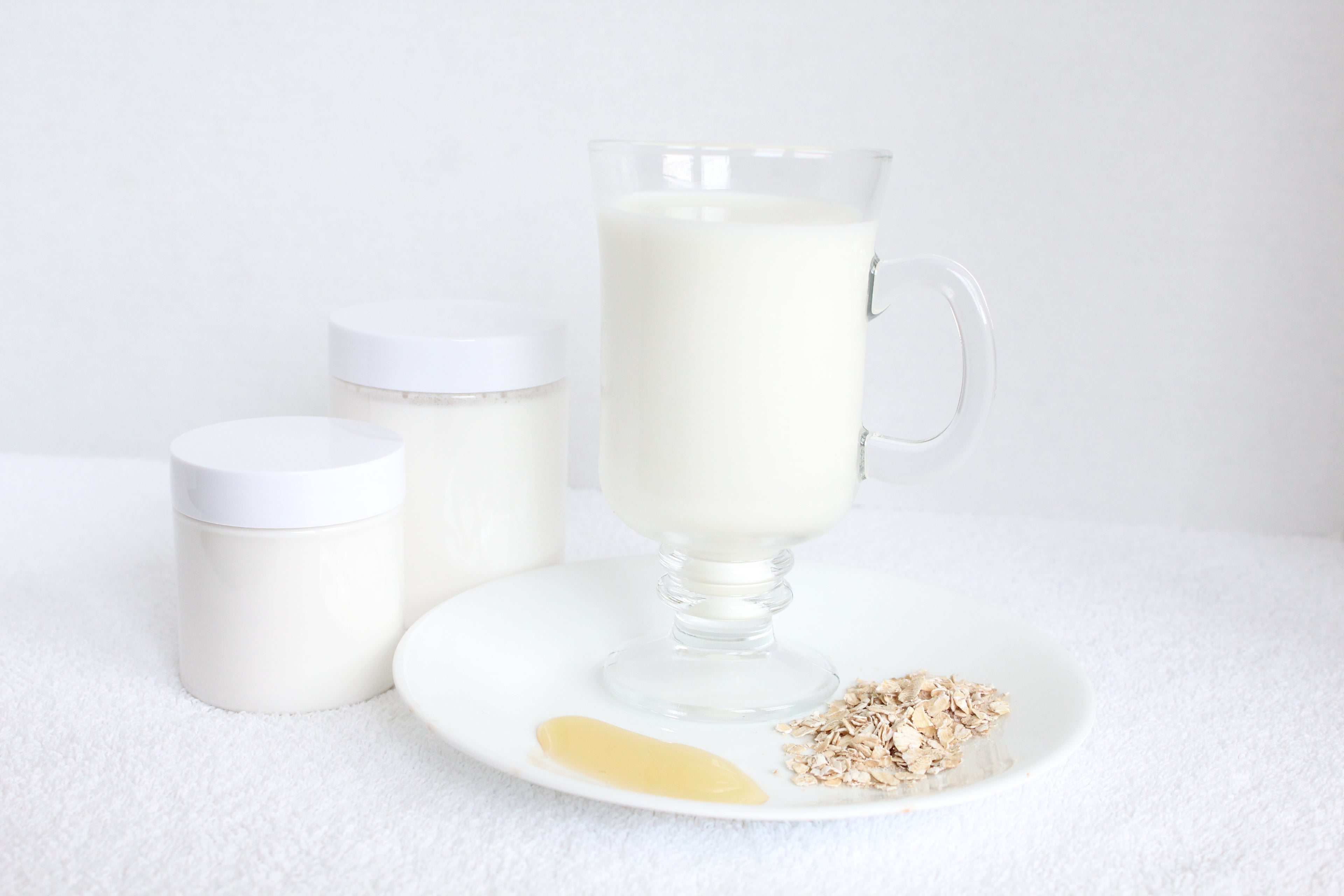 Glass of milk with a plate of oatmeal and a container on a white background