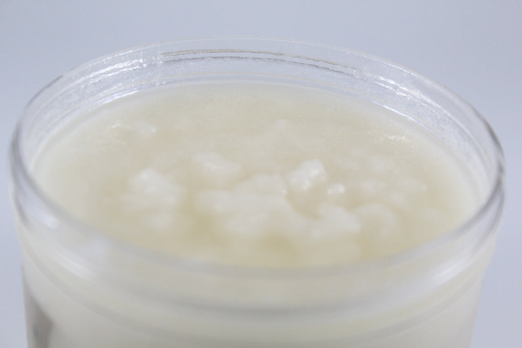 Jar of white sugar scrub on a light gray background