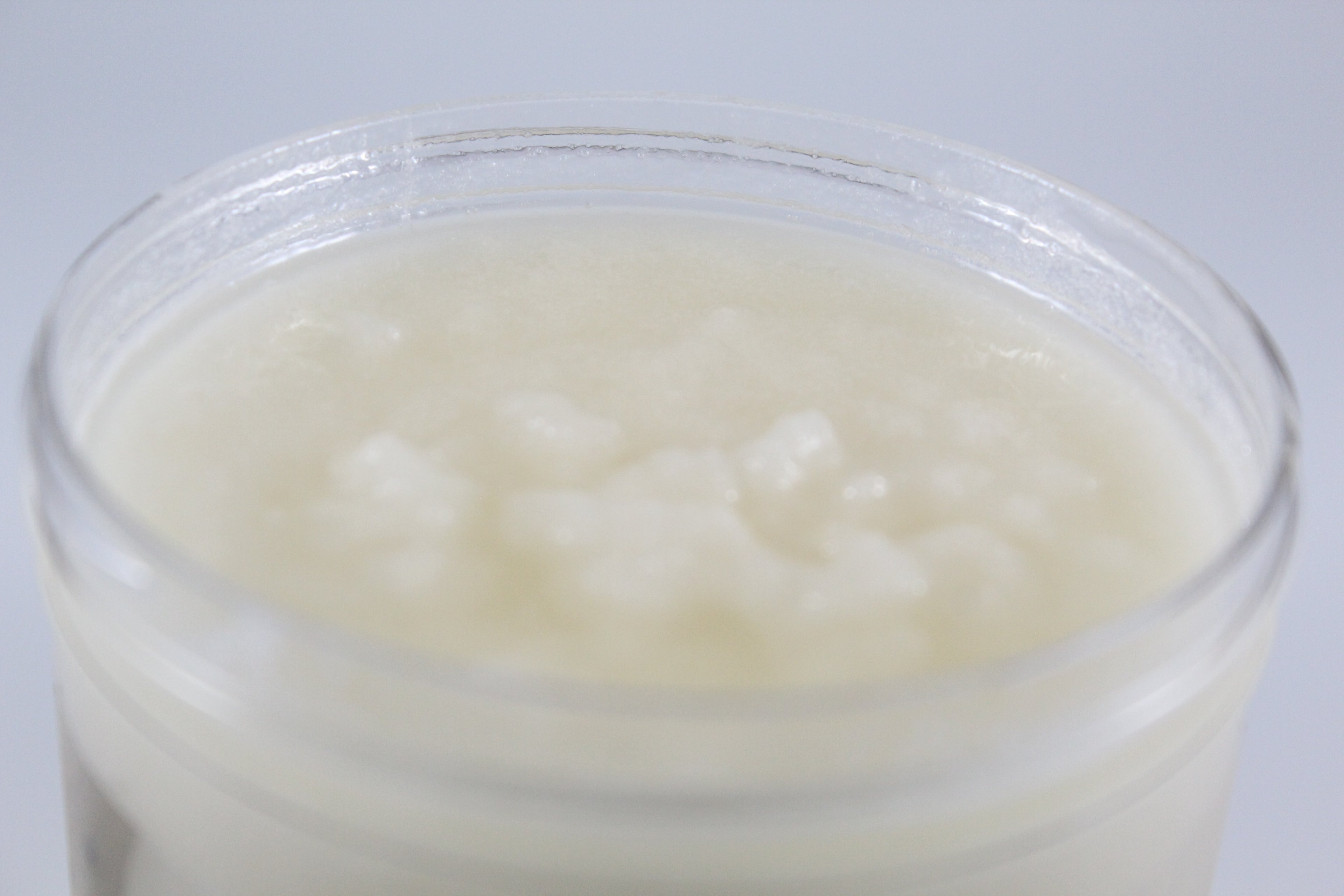 Jar of white sugar scrub on a light gray background