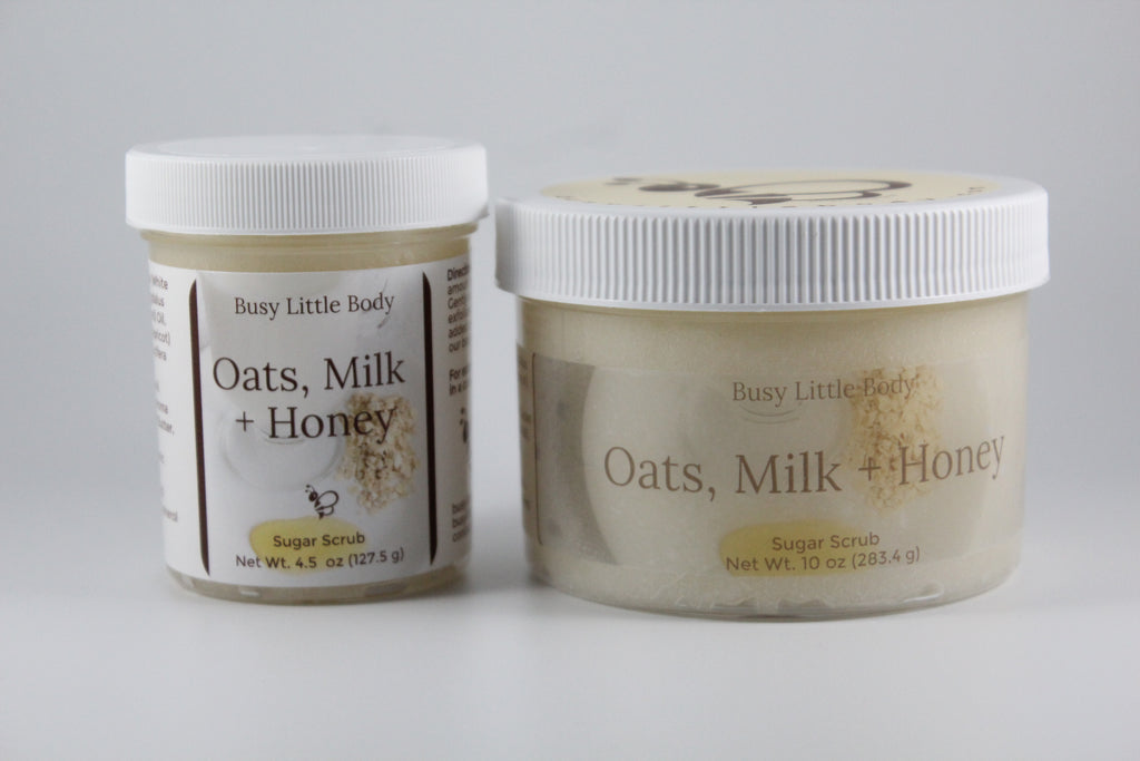 Two jars of 'Oats, Milk + Honey' sugar scrub by Busy Little Body on a gray background