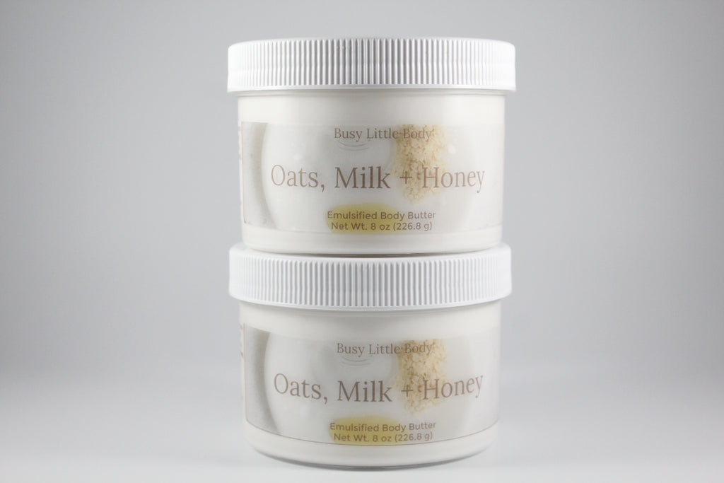 Two containers of Busy Little Body Oats, Milk + Honey body butter on a gray background