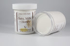 Two containers of 'Oats, Milk + Honey' emulsified body butter by Busy Little Body on a gray background.