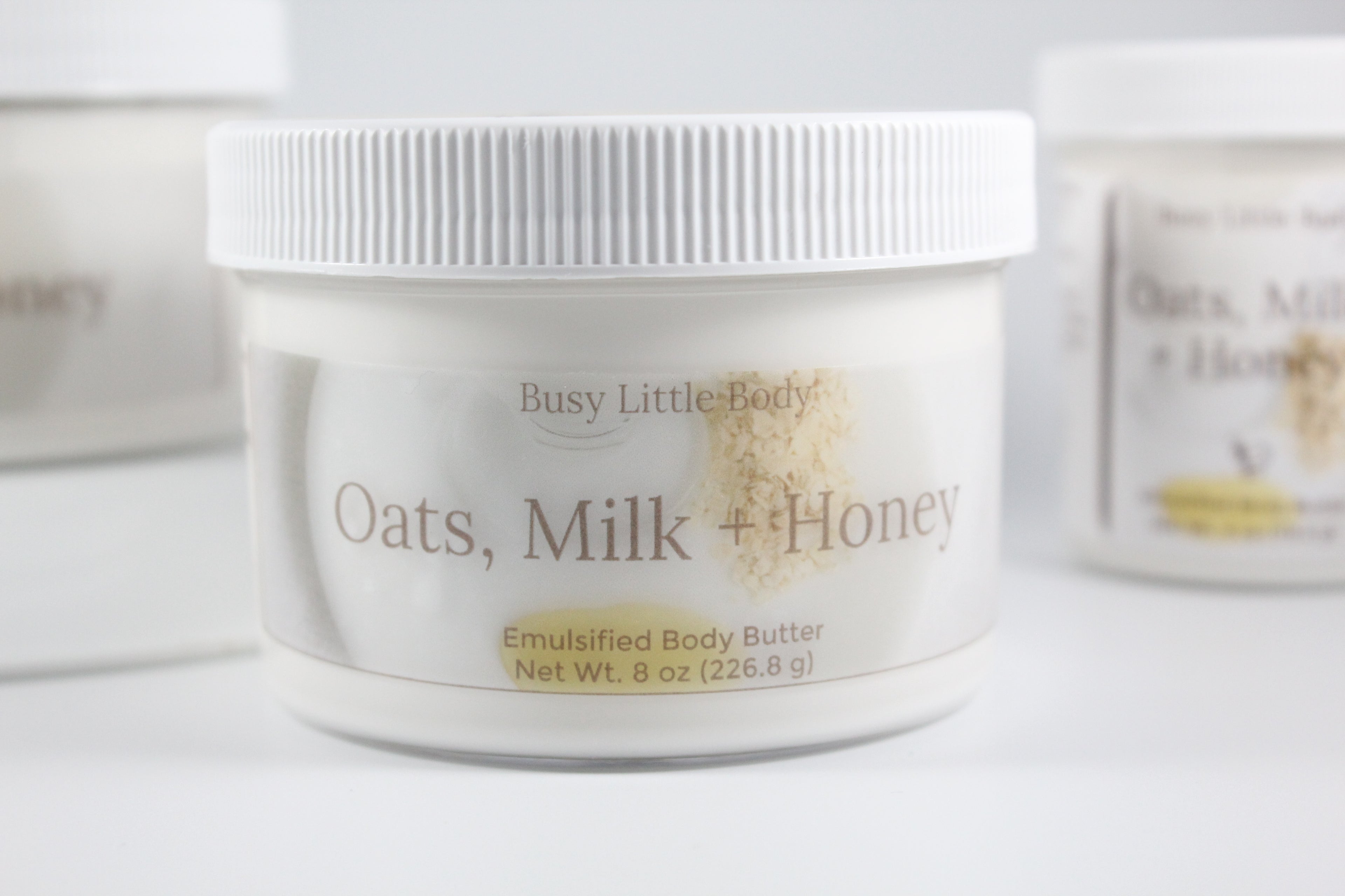 Jar of 'Oats, Milk + Honey' emulsified body butter by Busy Little Body on a white background.