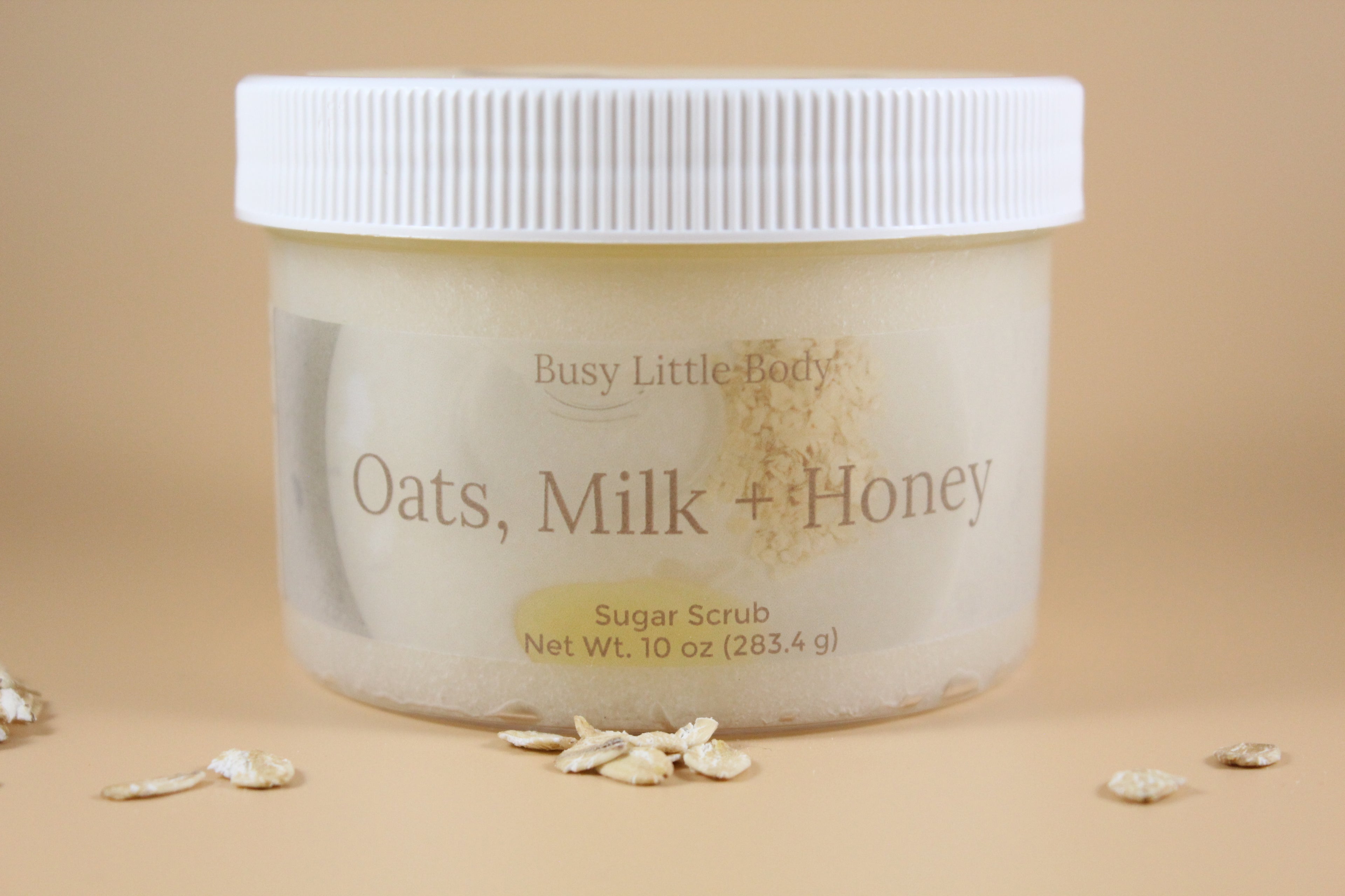 Jar of 'Oats, Milk + Honey' sugar scrub with a beige background