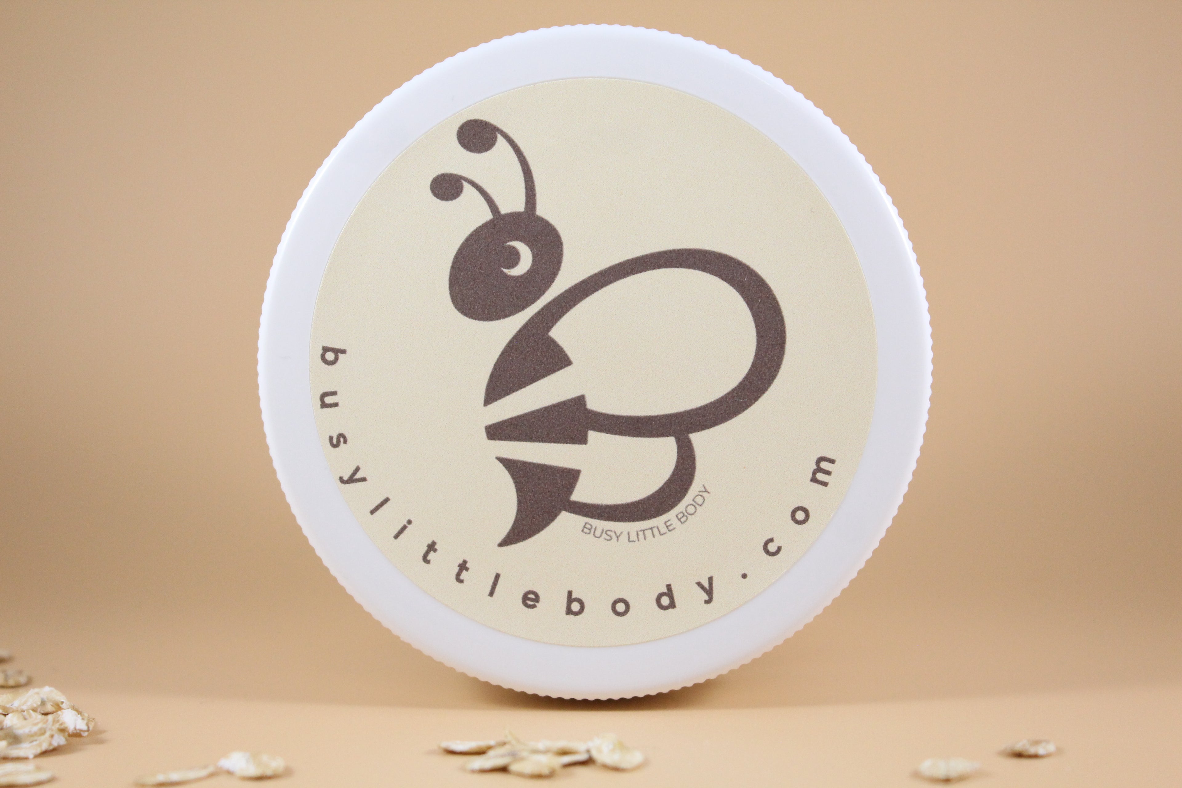 Round container with a bee logo and 'busylittlebody.com' text on a beige background