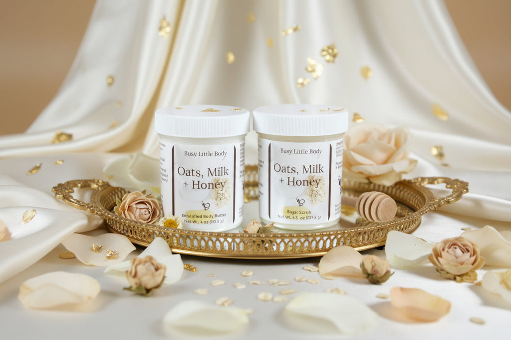 two jars of the goddess duo, a sugar scrub and a body butter with flowers, linen and a tray. cream background.