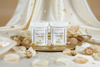 two jars of the goddess duo, a sugar scrub and a body butter with flowers, linen and a tray. cream background.