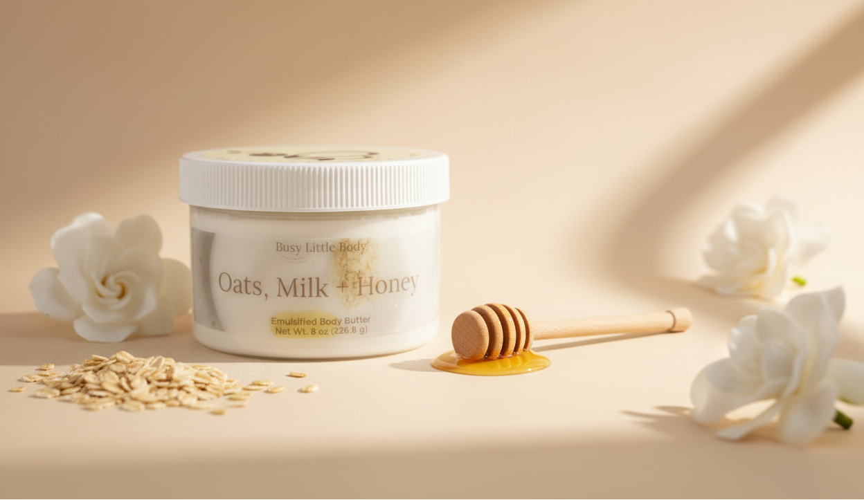 Jar of 'Oats, Milk & Honey' body butter with oats, a honey dipper, and flowers on a beige background